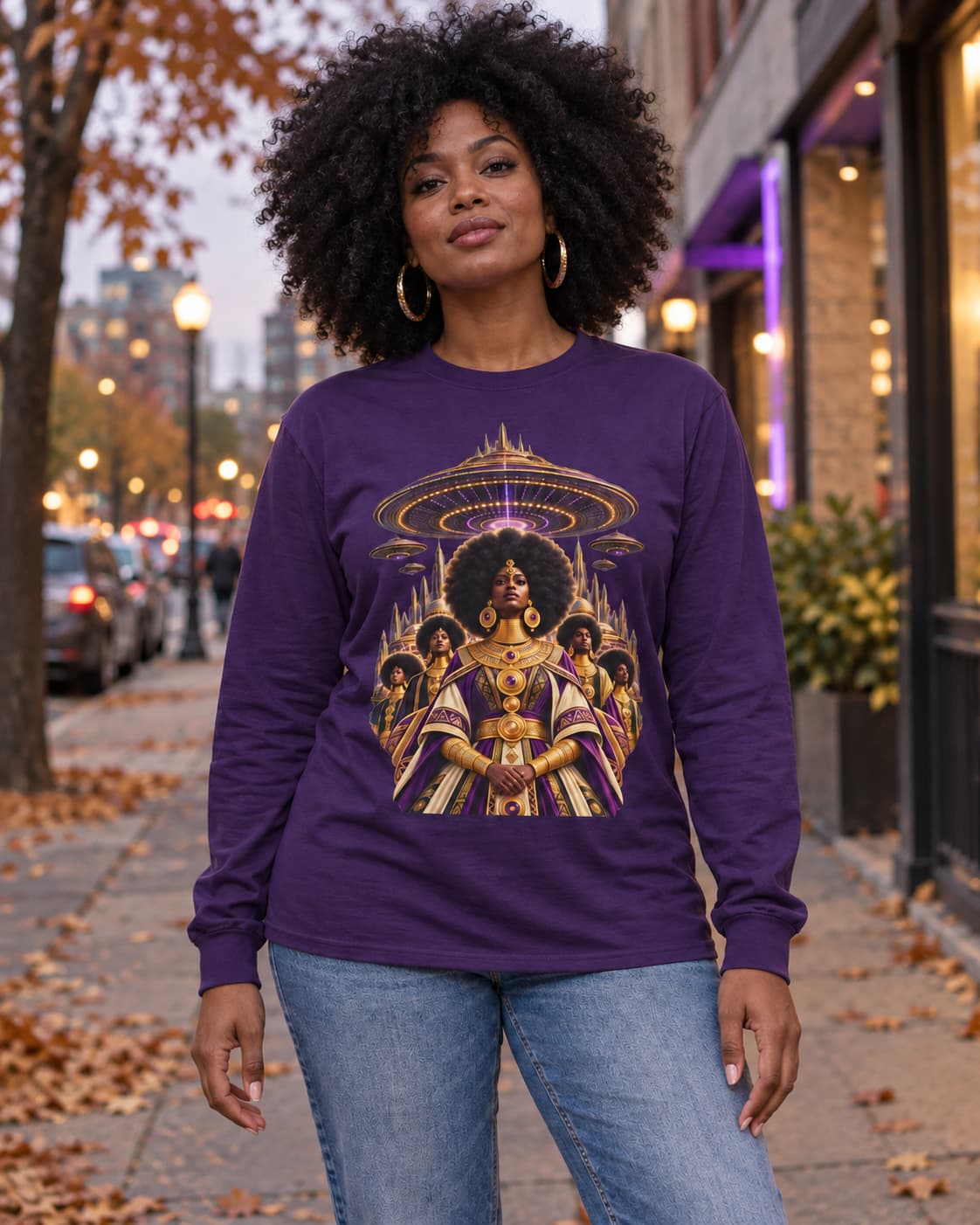 Woman wearing the purple Cosmic Queen long sleeve tee with jeans on a fall city street, JR Vortex Afrofuturist graphic