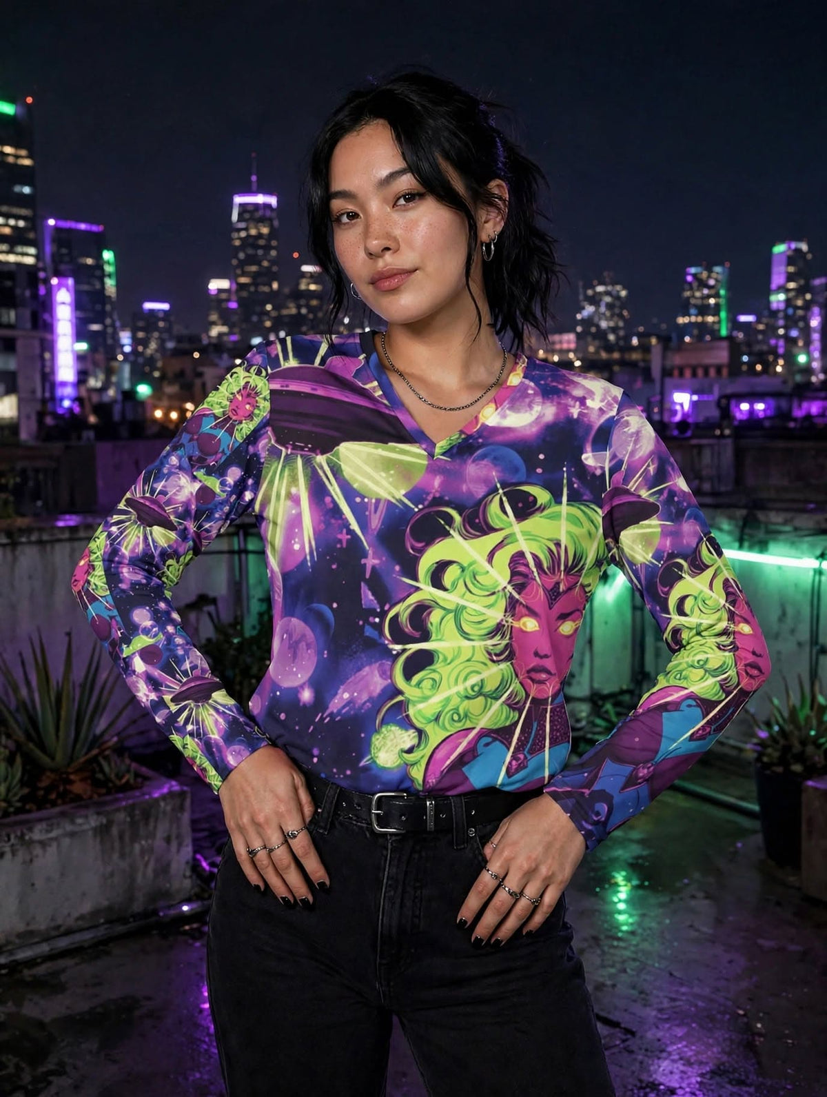 Woman wearing the Cosmic Siren V-Neck Long Sleeve neon space goddess shirt on a city rooftop at night